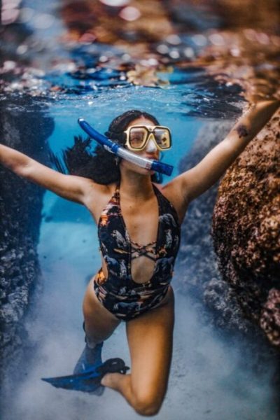 woman in blue and white floral swimsuit wearing white goggles